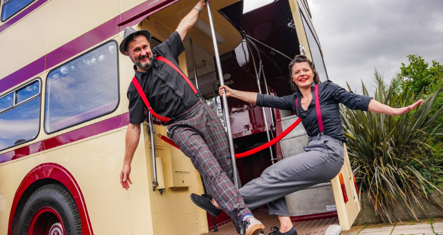 A couple of dancers pose on a vintage double decker bus